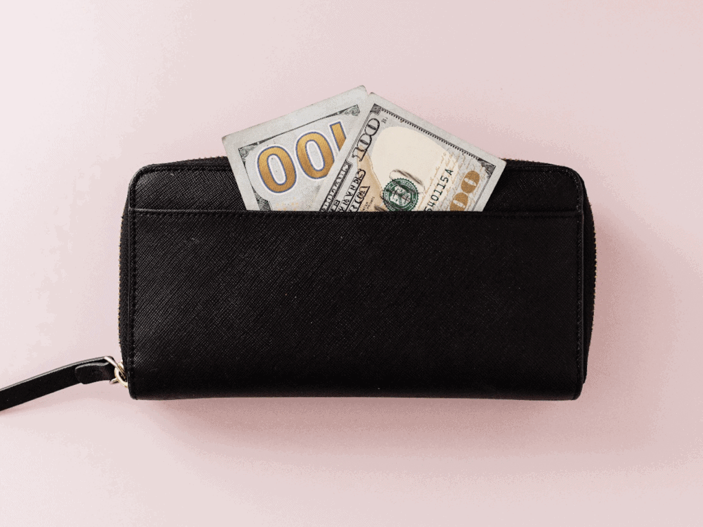 $100 bill in black wallet for the article How To Quickly Declutter Your Home and Make $500 This Weekend